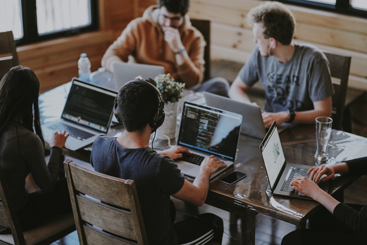 Small team working on laptops around a shared wooden table